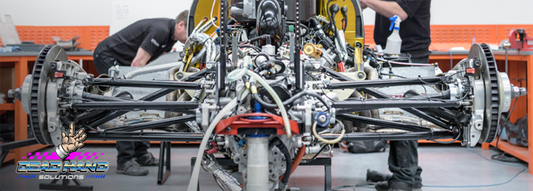 Image shows two individuals working on a motorsports chassis