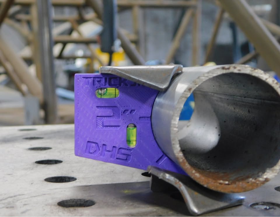Dead Hand Solutions Chassis Speed Jigs clipped onto round tubing, holding Trick tabs flush for tack welding on a race car chassis